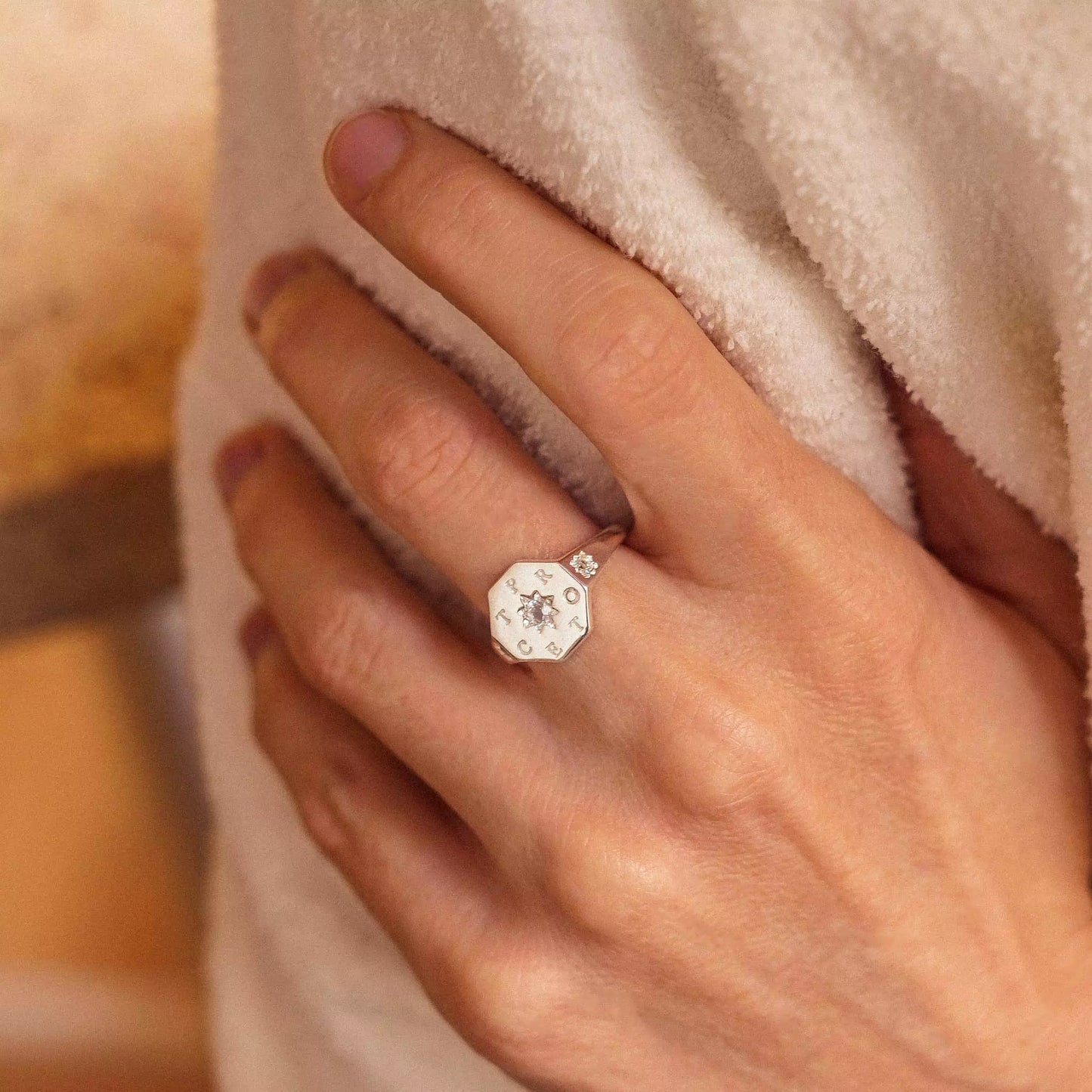 Bague chevalière femme personnalisable collection protect en argent gravée d'étoiles serties de pierres de zircon portant l'inscription gravée protect portée sur une main qui se tiens le bras