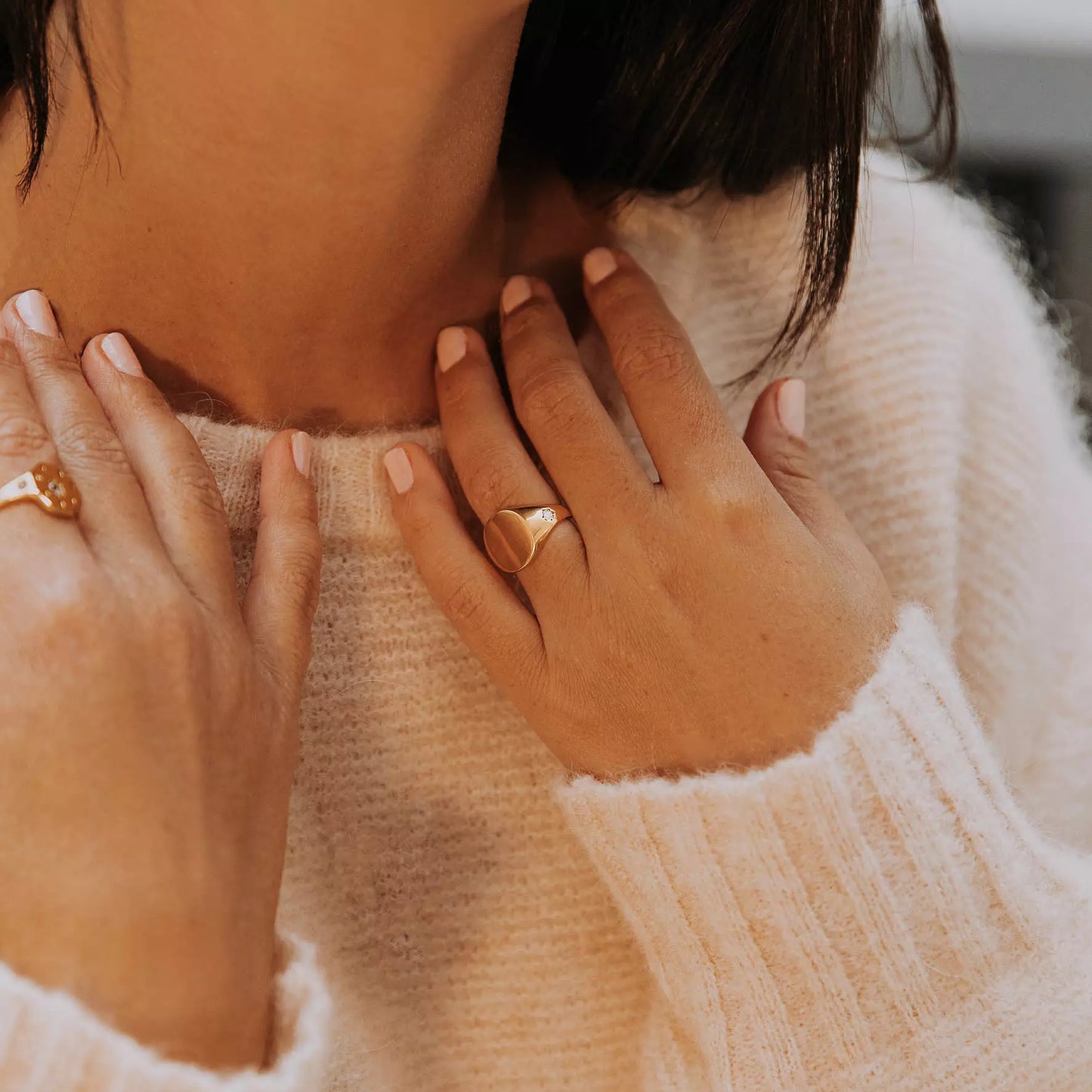 Bgaue femme toujours chevalière à gravure personnalisable en vermeil sertie de zircons couleur cristal sur les côtés portée à la main par une femme qui porte ses mains à son cou