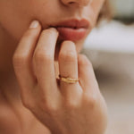 Bague femme collection amour en vermeil portant l'inscription gravée amour et portée par une femme pensive