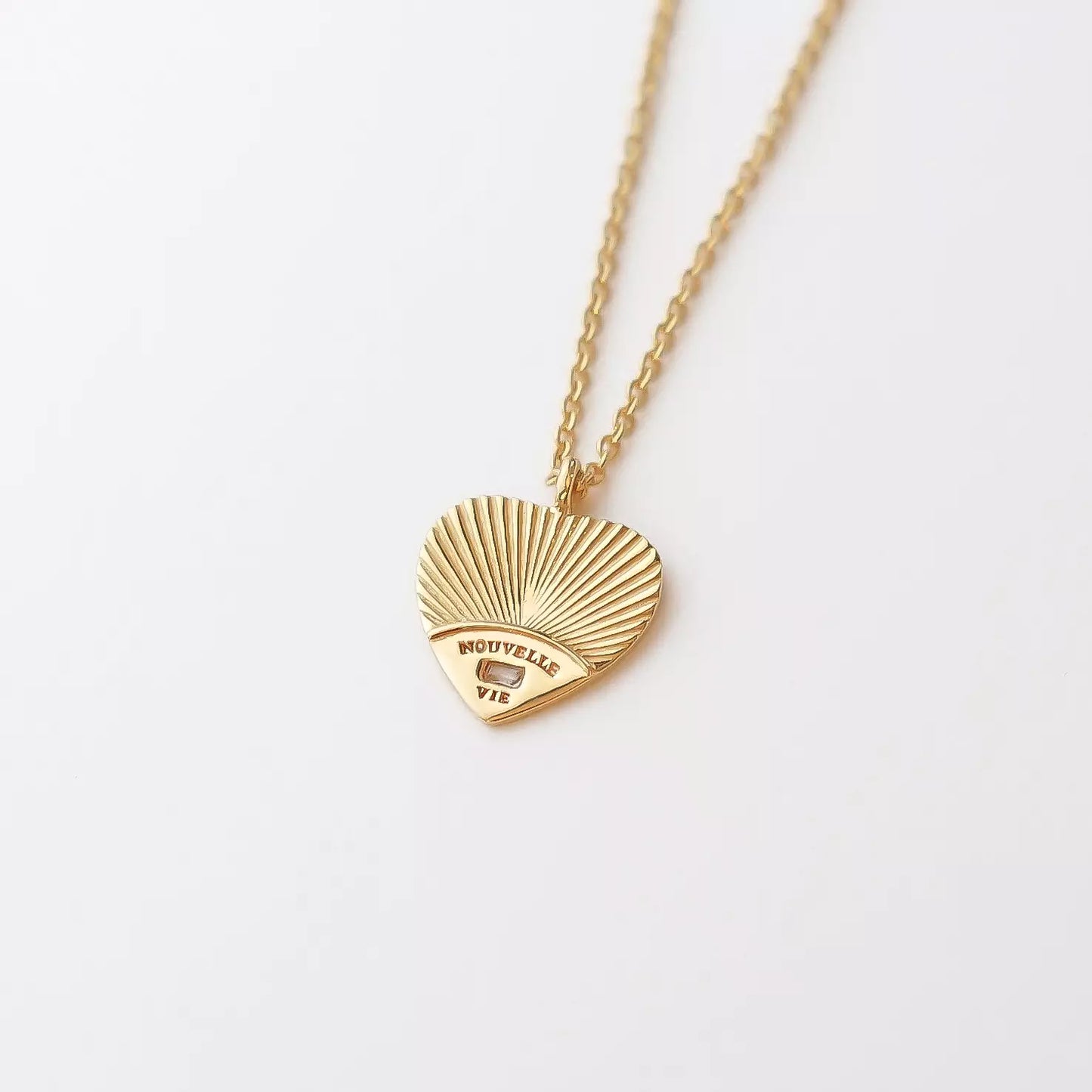 collier femme nouvelle vie en or à gravure personnalisable en forme de coeur et serti d'un zircon couleur cristal avec des gravures en rayons et les mots nouvelle et vie