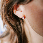 boucle d'oreille plaquée or nana cristal collection radieuse avec un serti de pierre en zircon de couleur cristal et un autre serti de zircon de couleur fuchsia portée par une femme